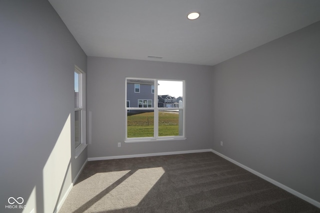 unfurnished room with dark colored carpet