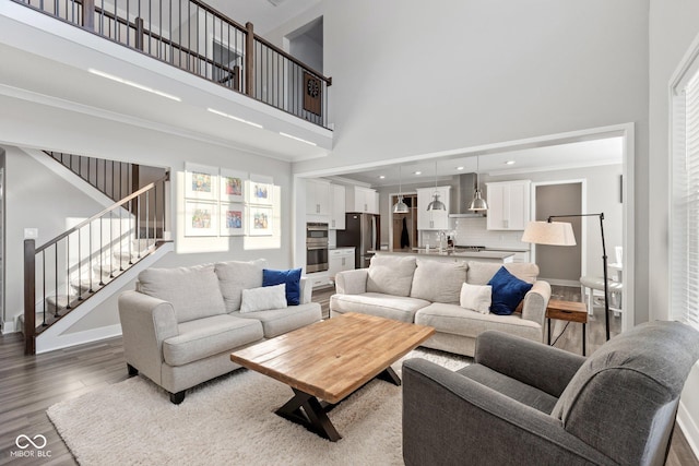 living room with a high ceiling, crown molding, and hardwood / wood-style floors