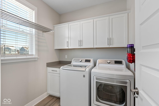 laundry area featuring separate washer and dryer, cabinets, and light hardwood / wood-style floors