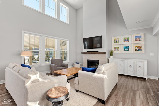 living room with a towering ceiling, crown molding, and hardwood / wood-style floors