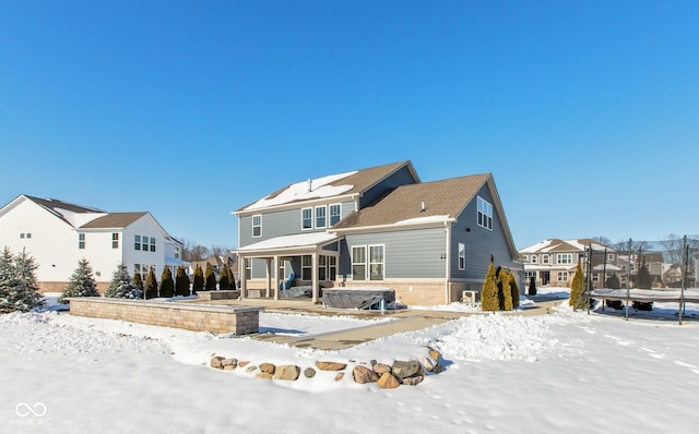 snow covered rear of property with a hot tub and a trampoline