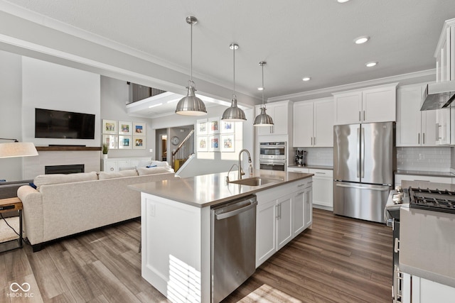 kitchen with sink, white cabinets, hanging light fixtures, a center island with sink, and appliances with stainless steel finishes