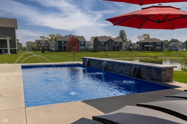 view of swimming pool with pool water feature, a lawn, and a water view