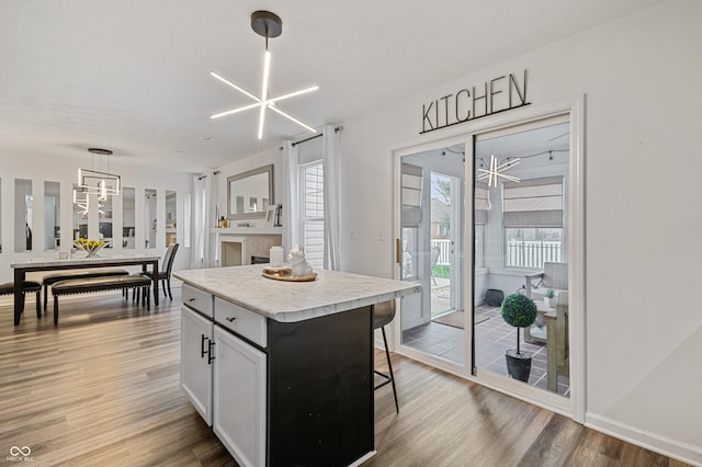 kitchen featuring white cabinets, a center island, hanging light fixtures, a notable chandelier, and light wood-type flooring