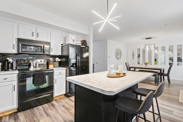 kitchen featuring black appliances, decorative light fixtures, a kitchen island, and white cabinets