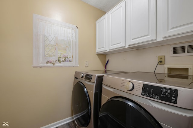 clothes washing area featuring cabinets, a textured ceiling, and washing machine and dryer