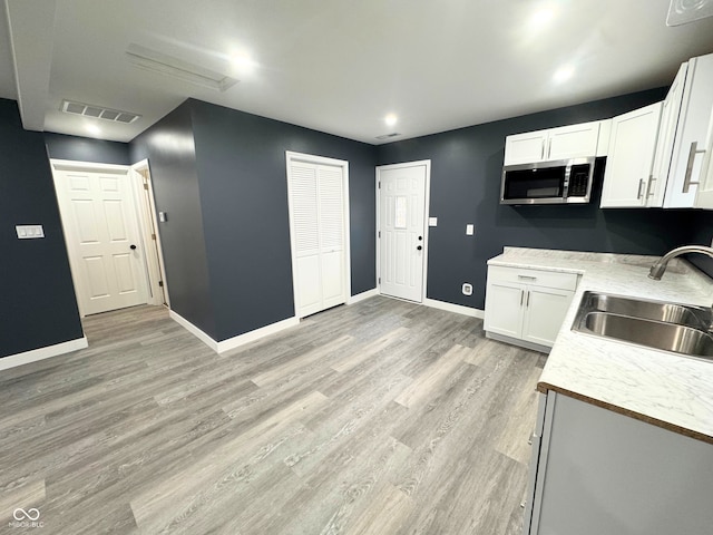 kitchen with sink, white cabinets, and light wood-type flooring