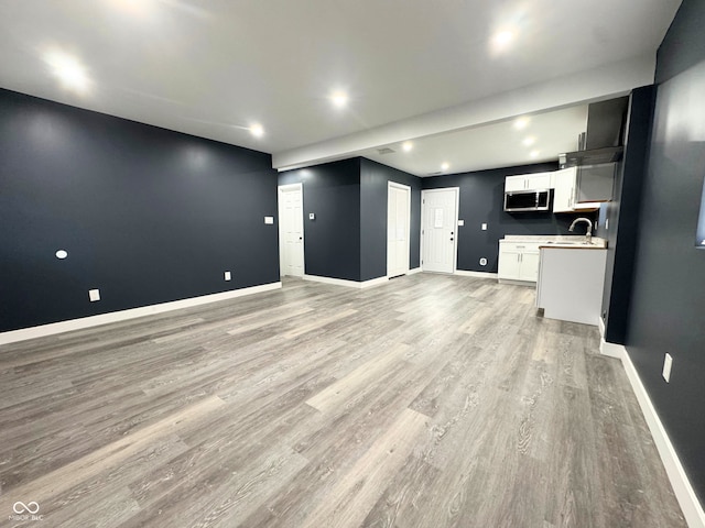 unfurnished living room featuring light wood-type flooring and sink