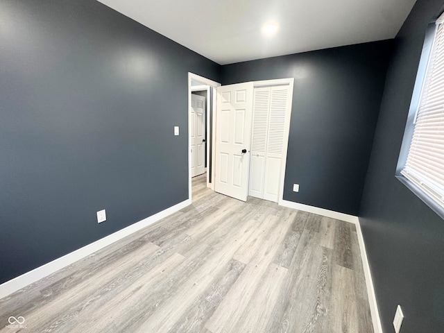 unfurnished bedroom featuring light hardwood / wood-style flooring and a closet