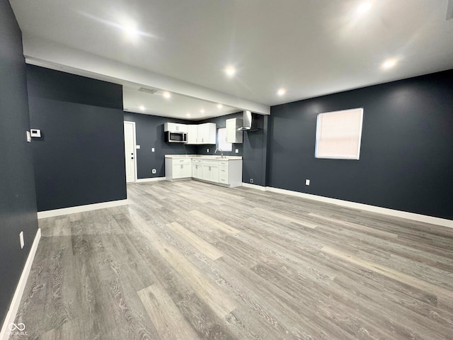 unfurnished living room with light hardwood / wood-style floors and sink