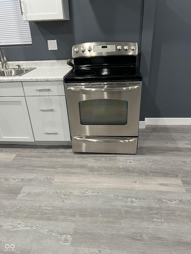 kitchen featuring sink, white cabinets, light hardwood / wood-style floors, and stainless steel range with electric stovetop