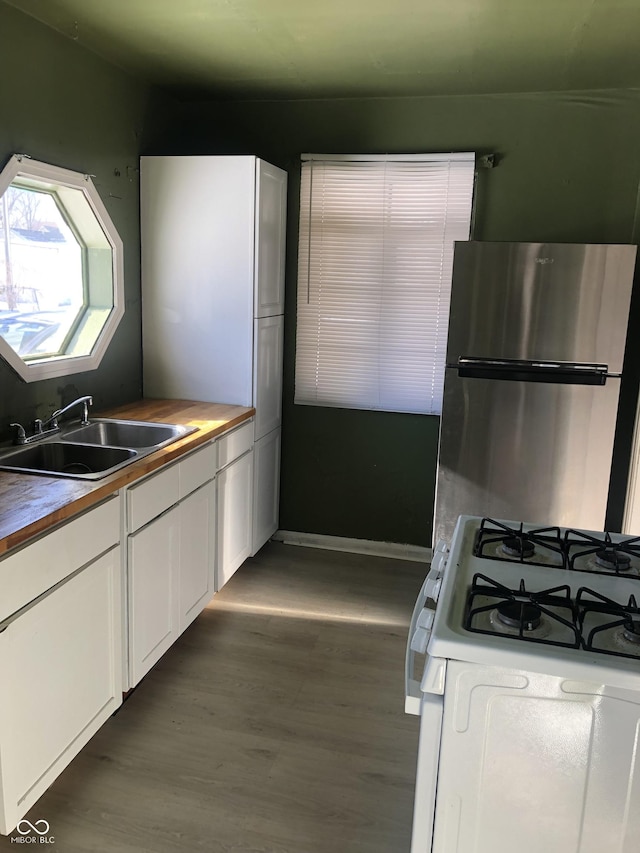 kitchen featuring sink, stainless steel fridge, white gas range oven, white cabinets, and dark hardwood / wood-style flooring