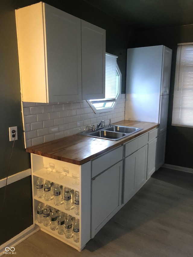 kitchen with wood counters, sink, white cabinetry, dark hardwood / wood-style floors, and decorative backsplash