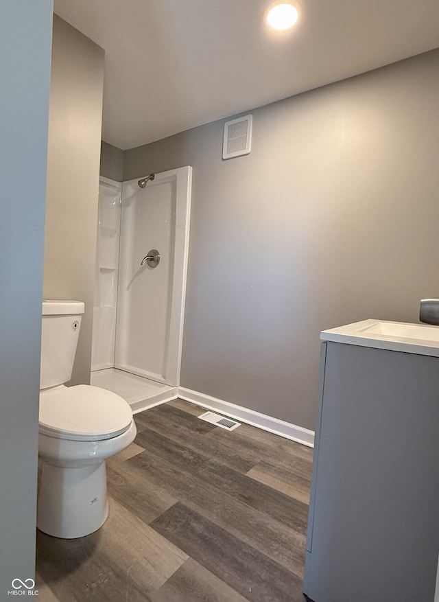 bathroom featuring toilet, a shower, vanity, and hardwood / wood-style floors