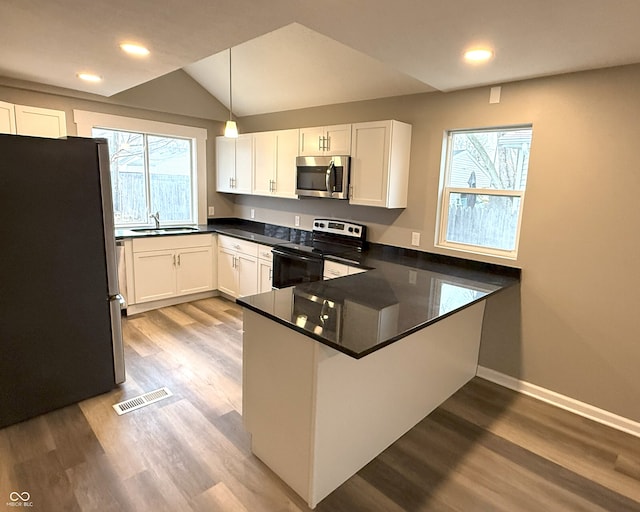 kitchen with stainless steel appliances, kitchen peninsula, pendant lighting, white cabinets, and sink