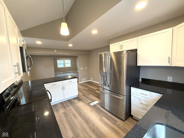 kitchen with white cabinets, light hardwood / wood-style flooring, dark stone counters, pendant lighting, and appliances with stainless steel finishes