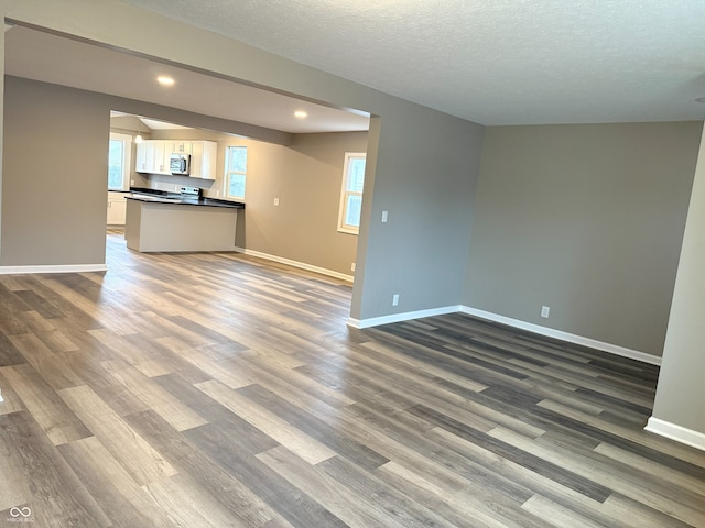 unfurnished living room with dark hardwood / wood-style flooring and a textured ceiling