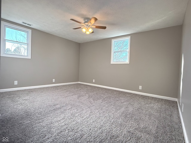 unfurnished room with a textured ceiling, ceiling fan, carpet flooring, and plenty of natural light