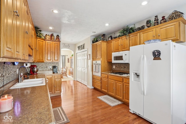 kitchen with light wood-type flooring, white appliances, backsplash, and sink