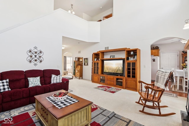 living room with a towering ceiling, light colored carpet, and ceiling fan