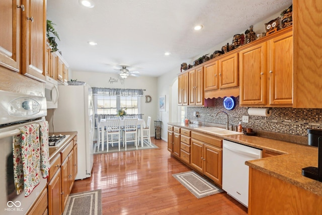 kitchen with white appliances, sink, light hardwood / wood-style flooring, ceiling fan, and decorative backsplash