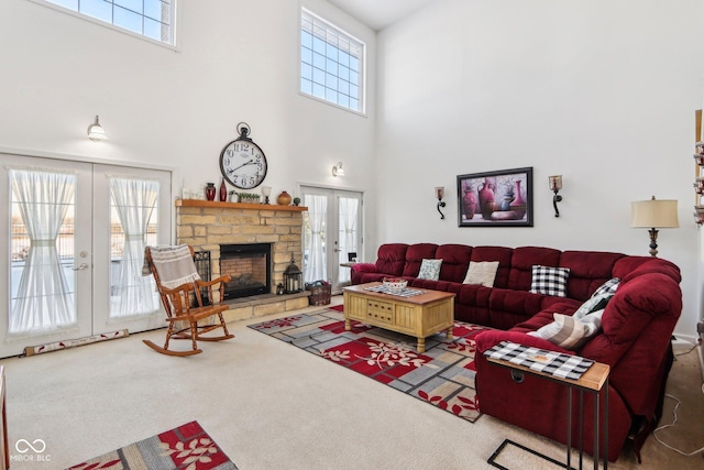 living room featuring a fireplace, a towering ceiling, carpet floors, and french doors