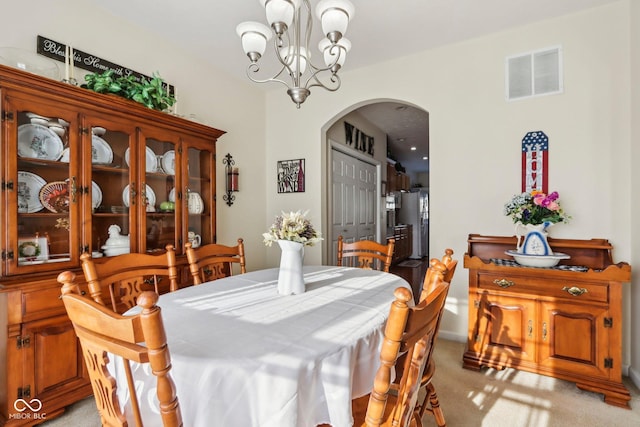 carpeted dining space featuring an inviting chandelier