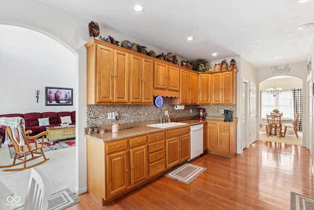 kitchen featuring sink, white dishwasher, light wood-type flooring, and an inviting chandelier