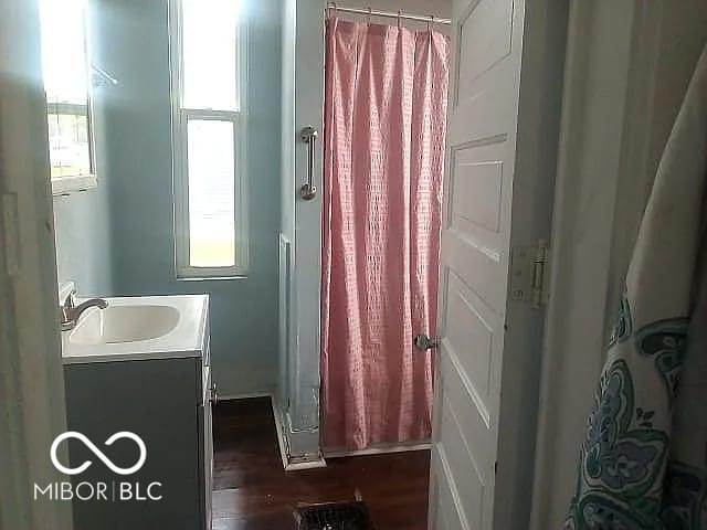 bathroom with curtained shower, vanity, and hardwood / wood-style flooring