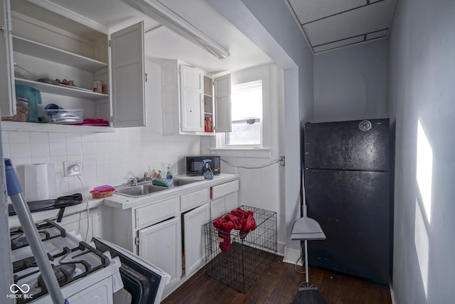 kitchen featuring backsplash, black appliances, sink, dark hardwood / wood-style flooring, and white cabinetry