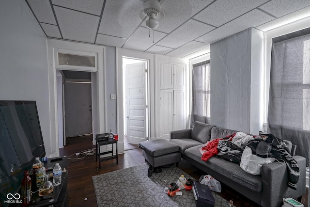 living room with a drop ceiling and dark wood-type flooring