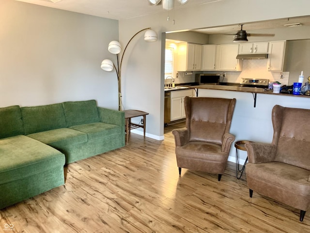 living room featuring ceiling fan, light hardwood / wood-style floors, and sink