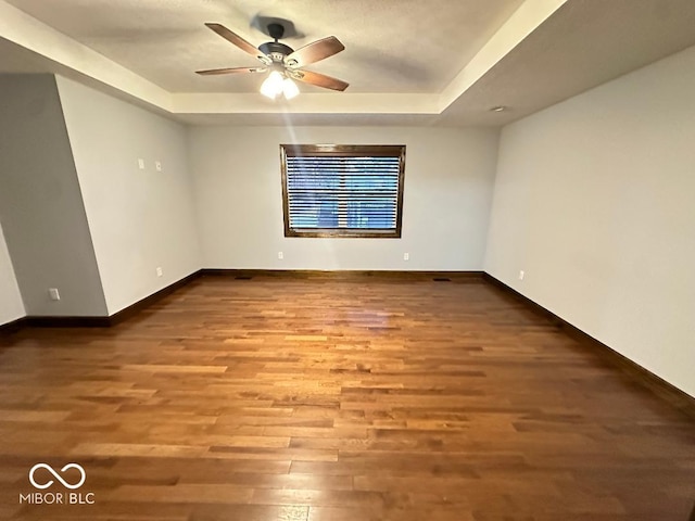 unfurnished room featuring hardwood / wood-style flooring, ceiling fan, and a tray ceiling