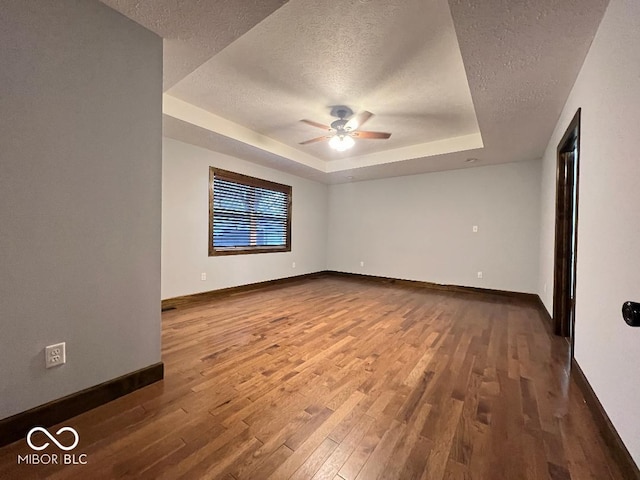 unfurnished room featuring hardwood / wood-style floors, ceiling fan, a raised ceiling, and a textured ceiling