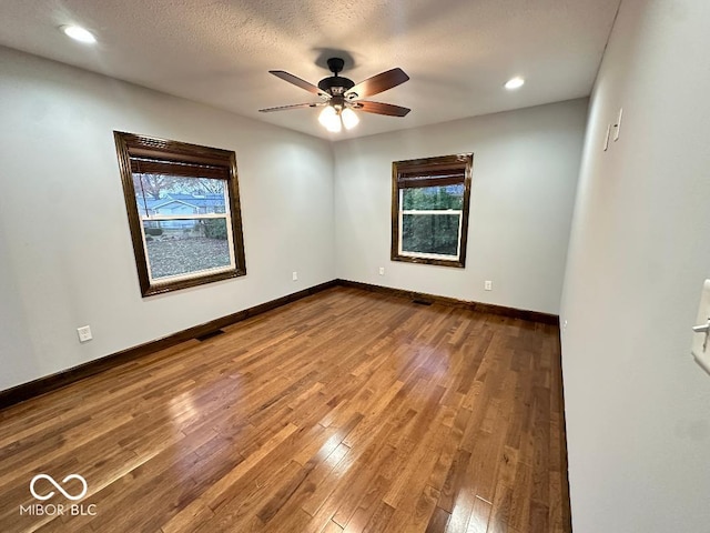 spare room featuring hardwood / wood-style floors, plenty of natural light, ceiling fan, and a textured ceiling