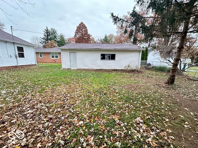 rear view of property with an outdoor structure and a lawn