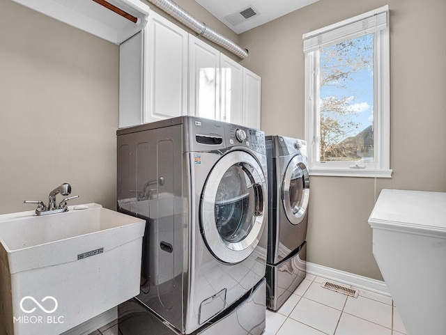 laundry room featuring cabinets, light tile patterned floors, washer and clothes dryer, and sink