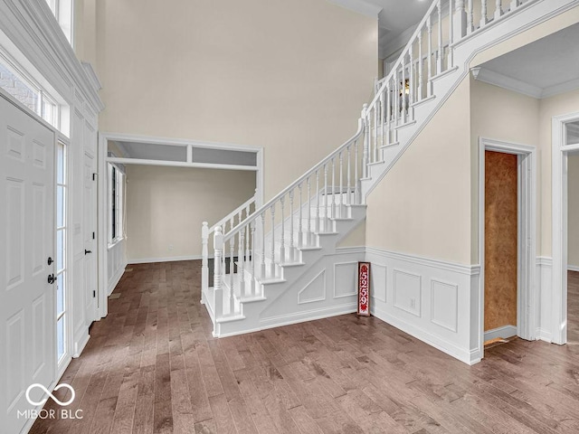 entrance foyer with hardwood / wood-style flooring, a towering ceiling, and crown molding