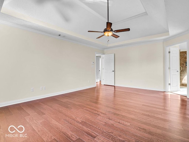 empty room featuring hardwood / wood-style flooring, crown molding, and a tray ceiling