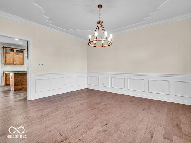 unfurnished room with hardwood / wood-style floors, a notable chandelier, and crown molding