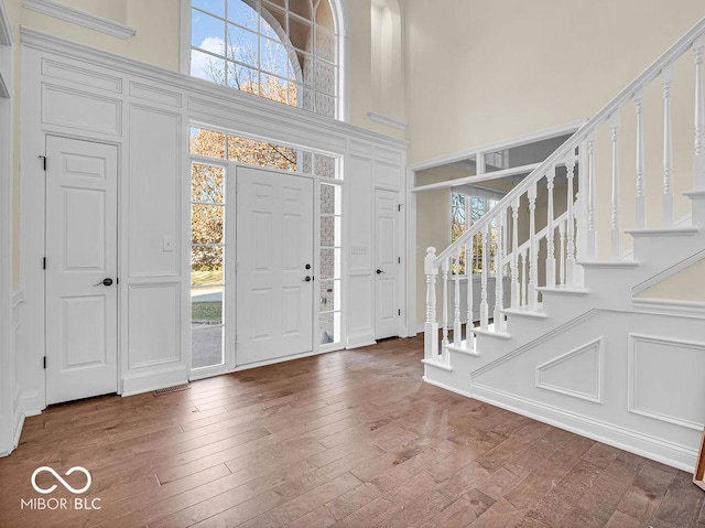 entryway with hardwood / wood-style floors and a towering ceiling