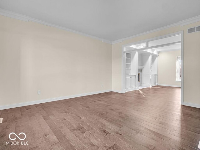 empty room featuring wood-type flooring and crown molding