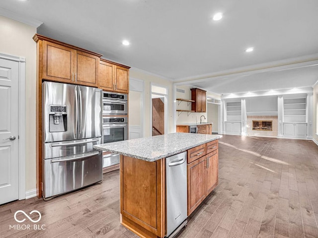 kitchen featuring light wood-type flooring, stainless steel appliances, and ornamental molding