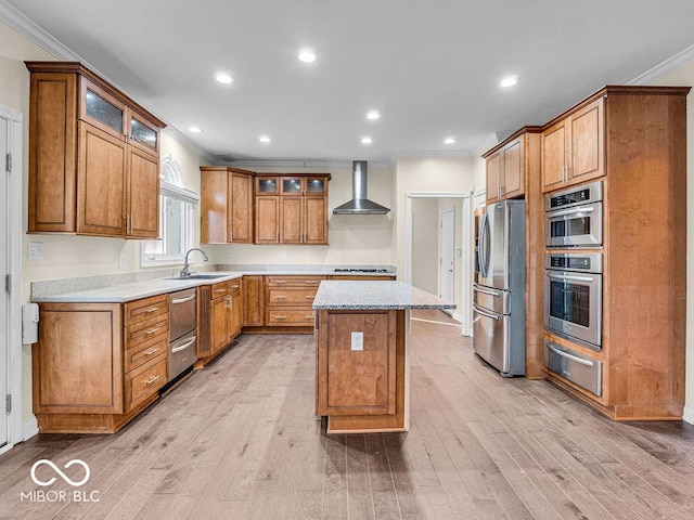 kitchen featuring a kitchen island, light wood-type flooring, wall chimney range hood, and appliances with stainless steel finishes