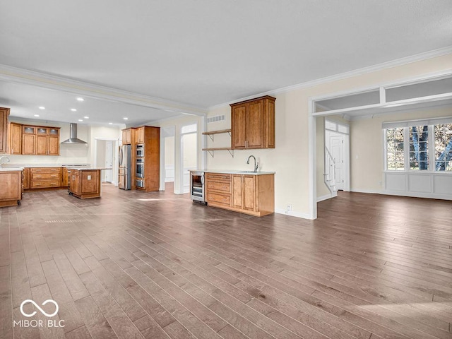 unfurnished living room featuring hardwood / wood-style flooring, beverage cooler, crown molding, and sink