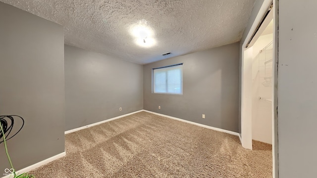 carpeted empty room with a textured ceiling