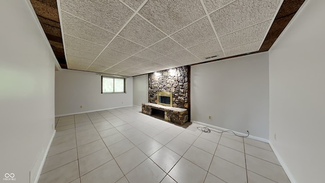 unfurnished living room with a drop ceiling, light tile patterned floors, and a fireplace