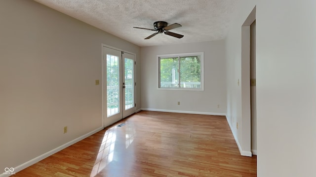 empty room with ceiling fan, light hardwood / wood-style floors, a textured ceiling, and french doors