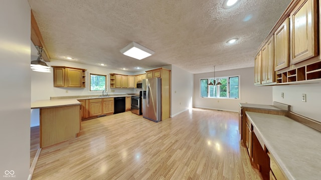 kitchen featuring sink, stainless steel appliances, hanging light fixtures, light hardwood / wood-style floors, and a textured ceiling