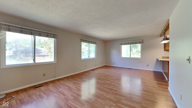 spare room with a textured ceiling and light hardwood / wood-style floors